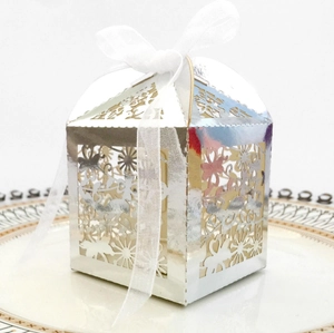 Close-up of laser-cut silver mirror candy box with butterfly floral patterns and white ribbon