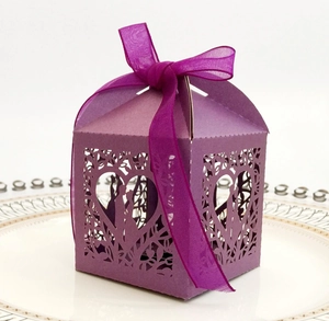 Detail of purple laser cut wedding favor box with floral patterns and organza ribbon