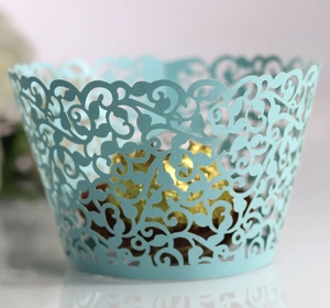 Macro detail of light blue laser-cut vine pattern cupcake wrapper with pearl paper texture