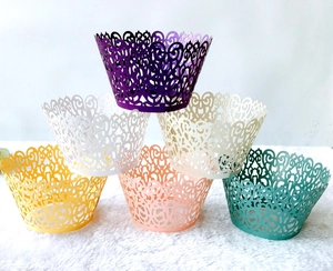 Laser-cut cupcake wrappers in various colors stacked on white plush background for parties