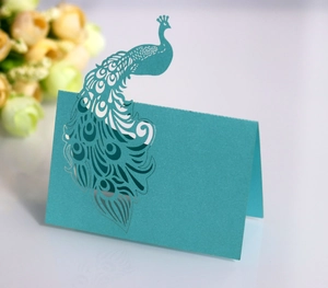 Detail of laser-cut peacock place card in teal pearlescent paper for wedding decor