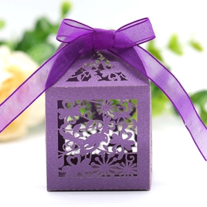 Close-up of purple laser-cut wedding favor box with floral patterns and satin ribbon