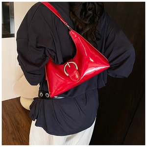 Detail of red patent leather hobo bag with a large silver metal buckle strap