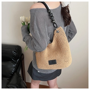 Detail of bohemian hollow knit shoulder bag with unique black bead strap and leather logo