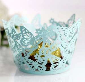 Macro shot of light blue laser-cut cupcake wrapper with butterfly and flower patterns