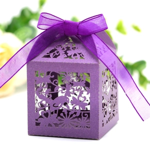 Macro shot of dark purple laser-cut candy box with bird patterns and satin ribbon bow
