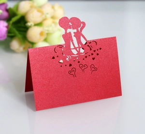 Detail of red glitter laser-cut wedding place card featuring a romantic couple silhouette