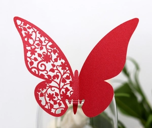 Detail of red glitter butterfly card with laser-cut floral pattern on a glass rim