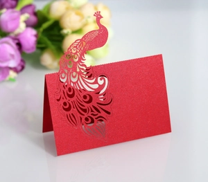 Detail of red laser-cut peacock place card with glitter texture and blank writing space
