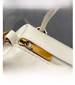 Macro detail of the white leather bag texture and smooth golden zipper closure