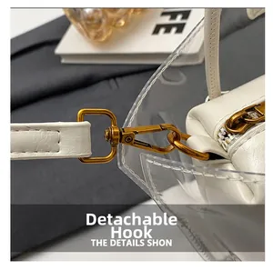 Close-up of golden metal hooks and white leather stitching on a transparent PVC tote bag