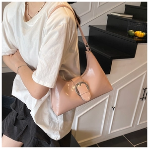 Detail of glossy pink hobo bag featuring a large silver buckle and slim shoulder strap