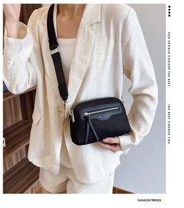 Détail du sac bandoulière en nylon noir avec large sangle porté par un mannequin