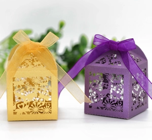 Detail of laser-cut gift boxes with intricate bird floral patterns and organza ribbons