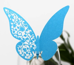 Detail of laser-cut sky blue butterfly place card attached to a crystal glass rim