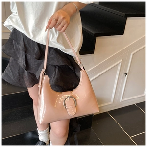 Detail of pink patent leather hobo bag with large silver buckle in a minimalist setting