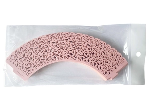 Macro detail of pink laser-cut floral cupcake wrappers in transparent plastic packaging