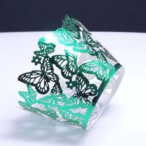 Macro view of emerald green laser-cut paper cupcake wrapper with butterfly pattern