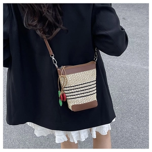 Detail of a woven rainbow bucket bag featuring cherry charms and premium faux leather trim