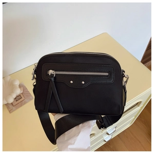 Détail d'un sac bandoulière en toile noire avec large sangle en nylon et zips argentés