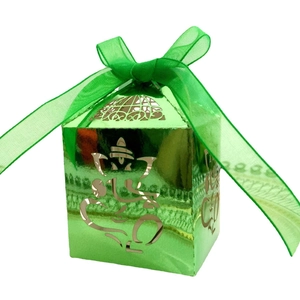 Detail of green metallic candy box featuring intricate Ganesha hollow-out carving and ribbon