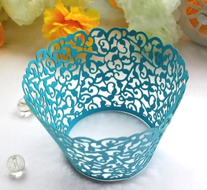 Detail of blue laser-cut cupcake wrappers with intricate vine hollow-out patterns