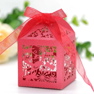 Detail of red laser-cut favor box with birds, hearts, and a red organza ribbon bow