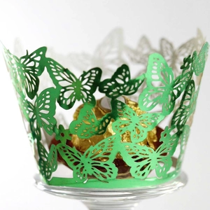 Detail of laser-cut green butterfly cupcake wrapper with intricate hollow patterns