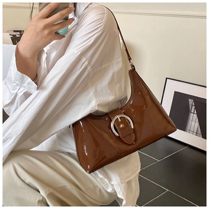 Detailed shot of dark brown patent leather shoulder bag with silver round buckle ornament