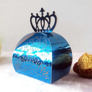 Blue laser-cut candy box with crown handle and intricate lace patterns next to chocolate
