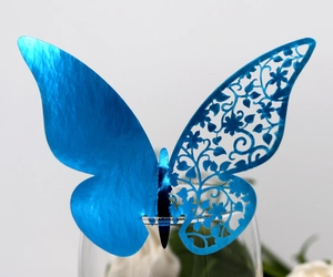 Detail of blue laser-cut butterfly place card with floral patterns on glass rim