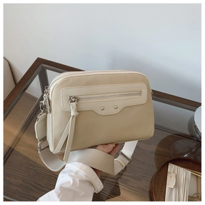 Détail du sac bandoulière beige avec zip à pompon et large bandoulière en nylon