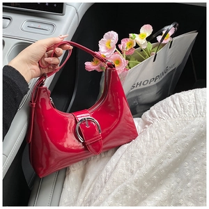 Detail of red patent leather shoulder bag with a large silver buckle on a car seat
