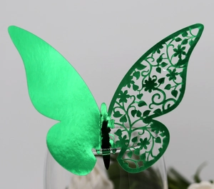 Detail of green 3D butterfly place card with laser-cut floral texture on a glass rim