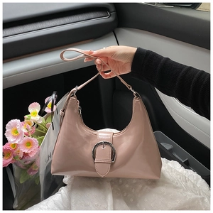 Detail of pink patent leather hobo bag featuring large silver buckle in a lifestyle setting