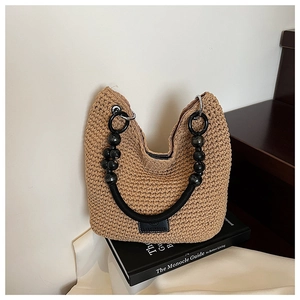 Detail of hand-woven crochet bag featuring black wax rope handle and metal ring accents