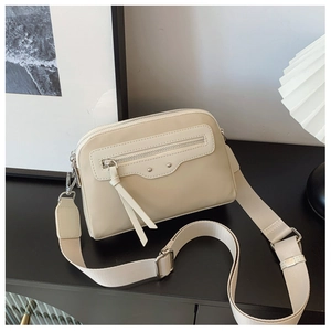 Détail du sac bandoulière beige avec large sangle tissée et accents métalliques