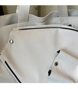 Close-up of white tote bag with silver snap button and Grey-white fabric label details