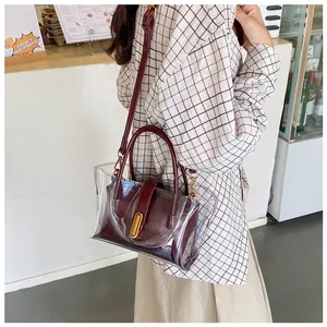 Detail view of transparent PVC tote bag with burgundy inner pouch and gold U-shaped buckle