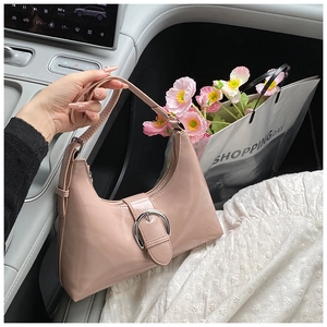 Detail of light pink patent leather hobo bag with silver round buckle inside a luxury car