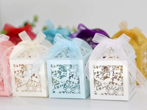 Detail view of laser-cut candy boxes with floral bird patterns and silk ribbons