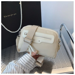 Détail d'un sac bandoulière beige avec fermetures éclair argentées et sangle large