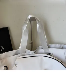 Close-up of wide white nylon shoulder strap and black piping on large tote bag