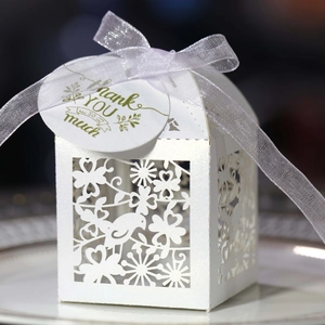 Detail of laser-cut bird and flower pattern on pearlescent gift box with silk ribbon