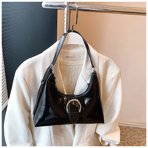 Detail of black glossy patent leather shoulder bag with silver round buckle adjustment