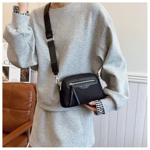 Détail du sac bandoulière en nylon noir avec clous argentés et longues tirettes à franges