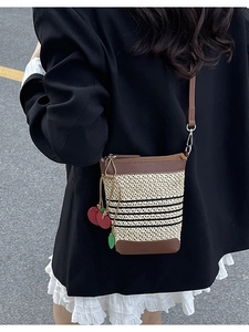 Summer rainbow woven straw bucket bag with leather trim and cherry charm on a model