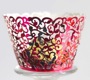 Macro detail of laser-cut floral cupcake wrappers in metallic pink finish with golden candy