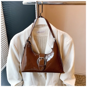 Macro shot of brown patent leather hobo bag with large silver round buckle detail