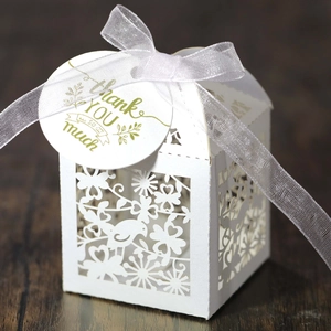 Detailed laser-cut wedding favor box with birds motif and Thank You tag on wood background